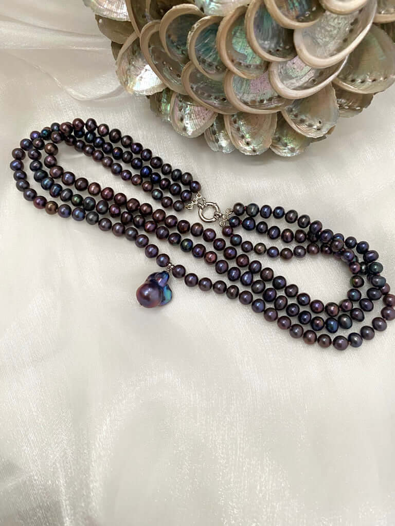 Black pearl necklace with a heart-shaped pendant on a white background