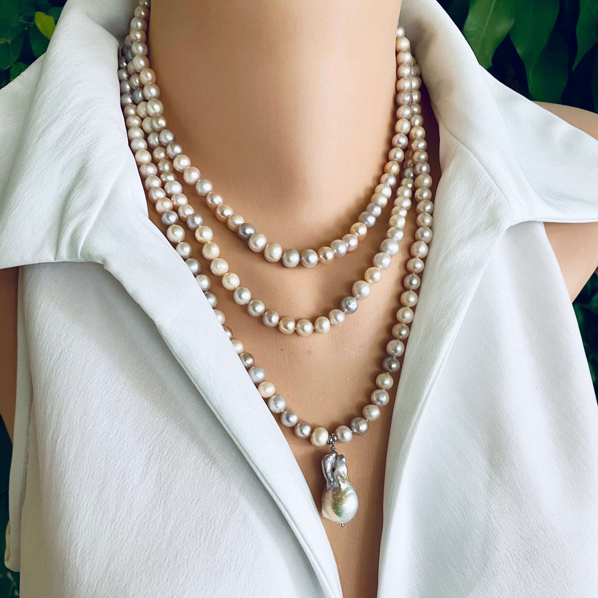 Pearl necklace draped over a white shirt with a blurred background