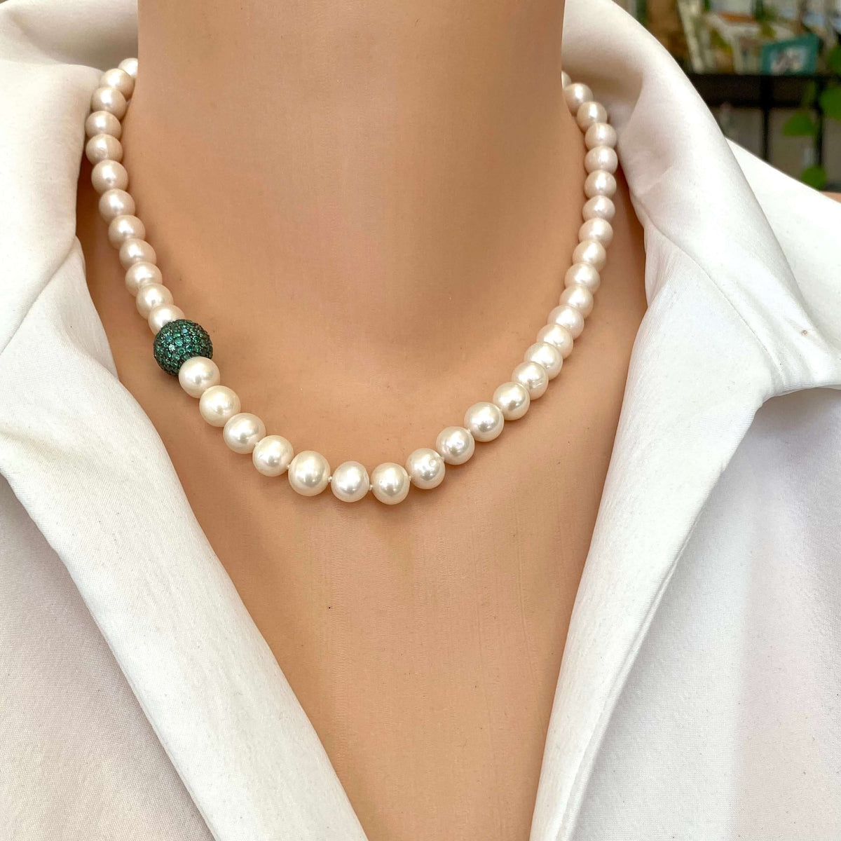 Pearl necklace with green CZ bead worn on a mannequin, showcasing handcrafted elegance and modern design.