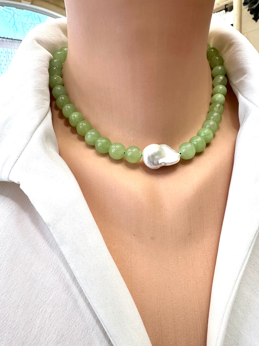 Necklace with green beads and a shell pendant on a white shirt