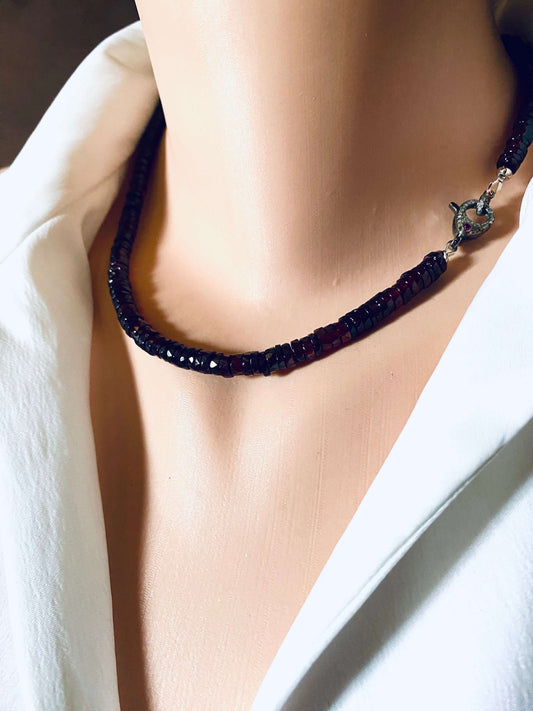 Garnet beaded necklace with diamond and ruby pavé clasp displayed on a mannequin against white fabric.