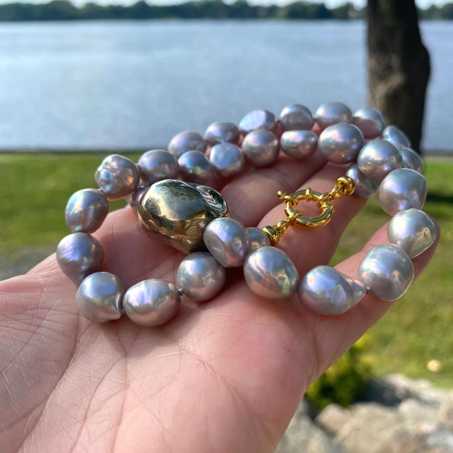 Grey pearl necklace with gold marine clasp photographed outdoors showing pearl luster and clasp