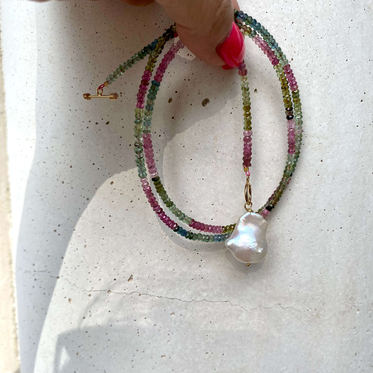Tourmaline baroque pearl toggle necklace displayed flat showing gemstone strand and pearl charm