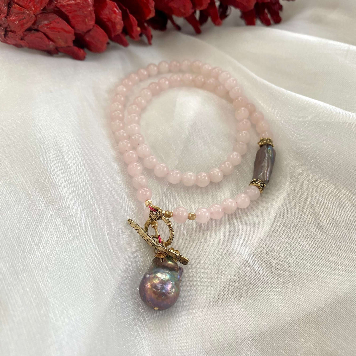Rose quartz toggle necklace with black baroque pearl, showcasing delicate design and blush-pink tones.