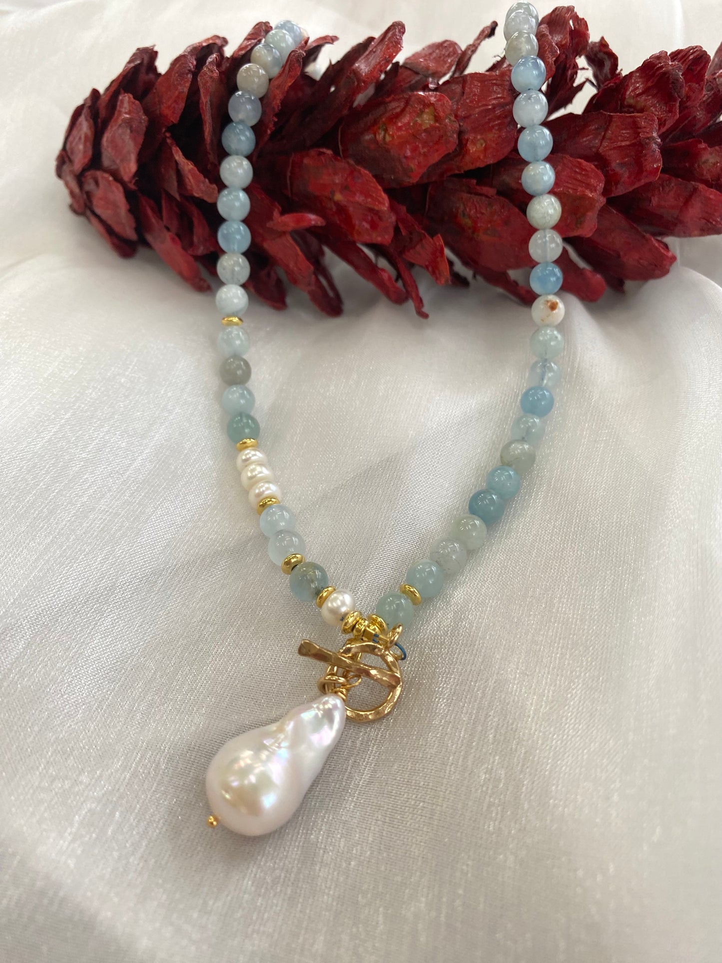 Aquamarine pearl necklace laid flat on white cloth, close-up detail