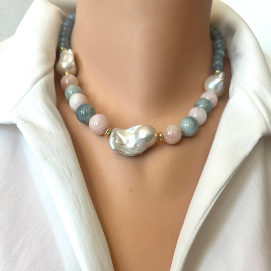A close-up of a double-strand beaded necklace worn on a mannequin neck. The necklace features a large irregular baroque pearl in the center, flanked by light blue, pale pink, and white beads separated by small gold spacer beads.