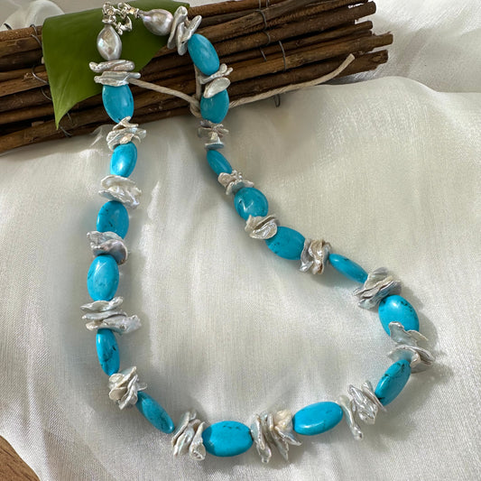 Chunky turquoise and silver grey keshi pearl necklace displayed on white cloth background