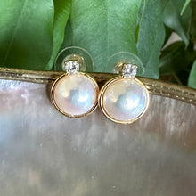 Lade das Bild in den Galerie-Viewer, Close-up of Mabe Edison pearl stud earrings with cubic zirconia halo on shell and leaf background
