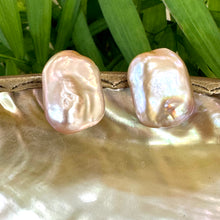 Carica l'immagine nel visualizzatore di Gallery, Golden pink rectangle baroque pearl stud earrings hanging from white pearl shell with green leaf background, designed and handmade in Canada.