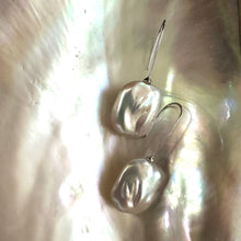 Load image into Gallery viewer, White freshwater pearl drop earrings rhodium version resting on shell beside green leaves, handcrafted jewelry from Canada.