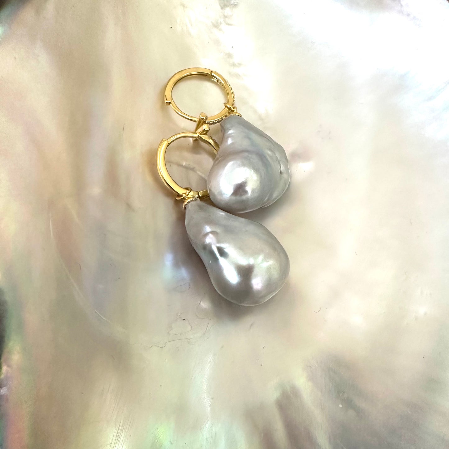 Grey baroque pearl hoop earrings resting on pearl shell backdrop, gold vermeil hoops handmade in Canada.