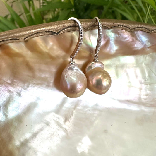 Golden pink baroque pearl dangle earrings hanging from white pearl shell, elegant handcrafted jewelry from Canada.
