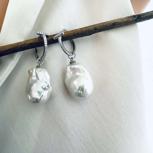 White Baroque Pearl Earrings – silver close-up against white cloth backdrop.