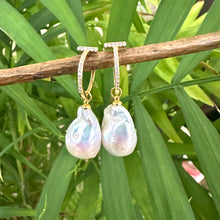Cargar imagen en el visor de la galería, White Baroque Pearl Earrings – gold version held by hand against green leaf backdrop