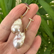 Charger l'image dans la galerie, Pink baroque pearl hoop earrings held in hand against green foliage, designed and handmade in Canada.