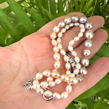 Carica l'immagine nel visualizzatore di Gallery, Pastel Rice Pearl Necklace displayed in hand with natural green leaf backdrop for detail.