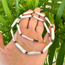 Load image into Gallery viewer, Close-up of biwa pearl and black opal necklace in hand, natural light setting