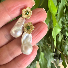 Cargar imagen en el visor de la galería, Chrome diopside pearl earrings held in hand for size comparison against green leaf background