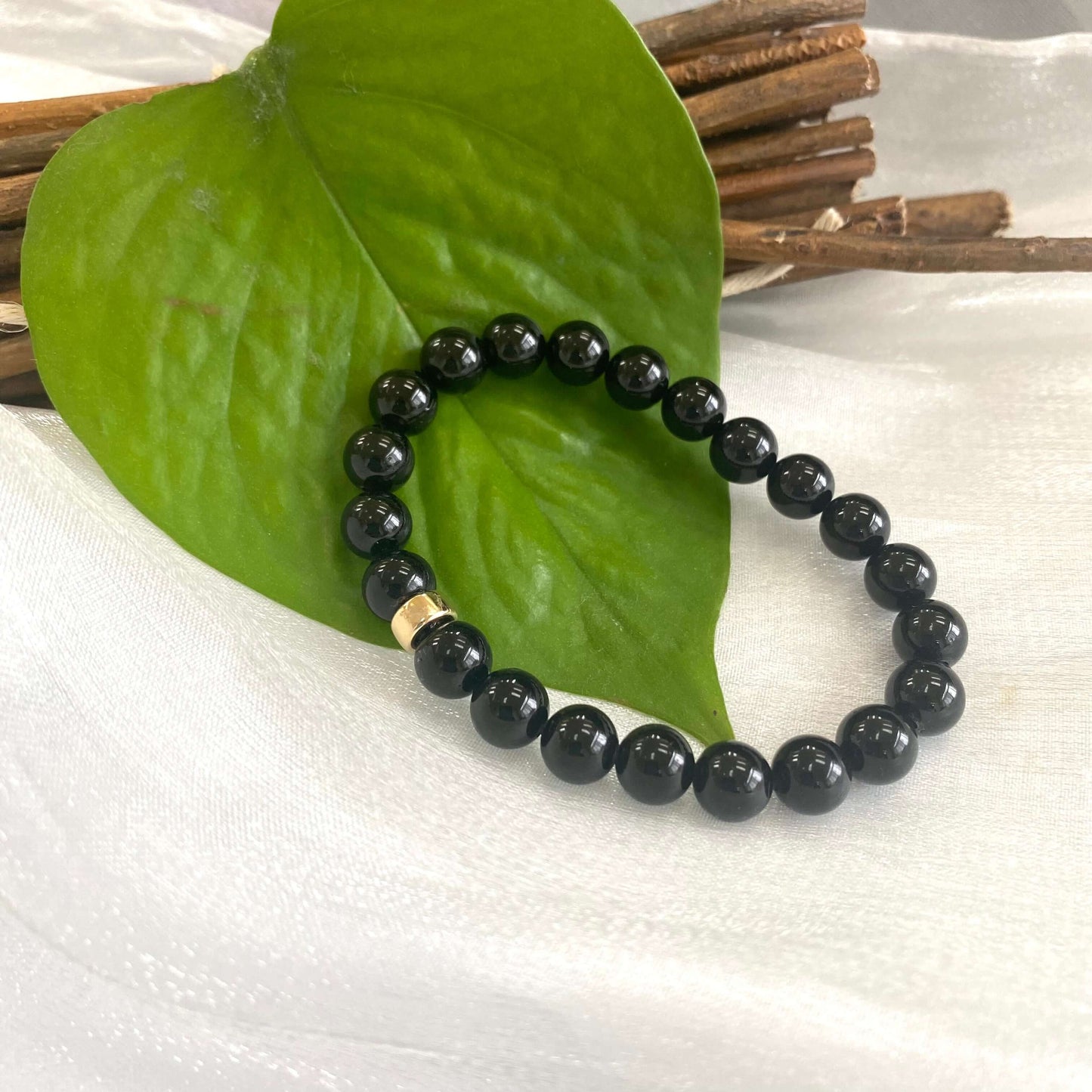 Black Tourmaline Bracelet – 8mm Beads with 14K Gold Filled accent on a leaf backdrop.