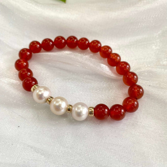 Orange Carnelian Bracelet with three pearls displayed on white cloth – detailed close-up