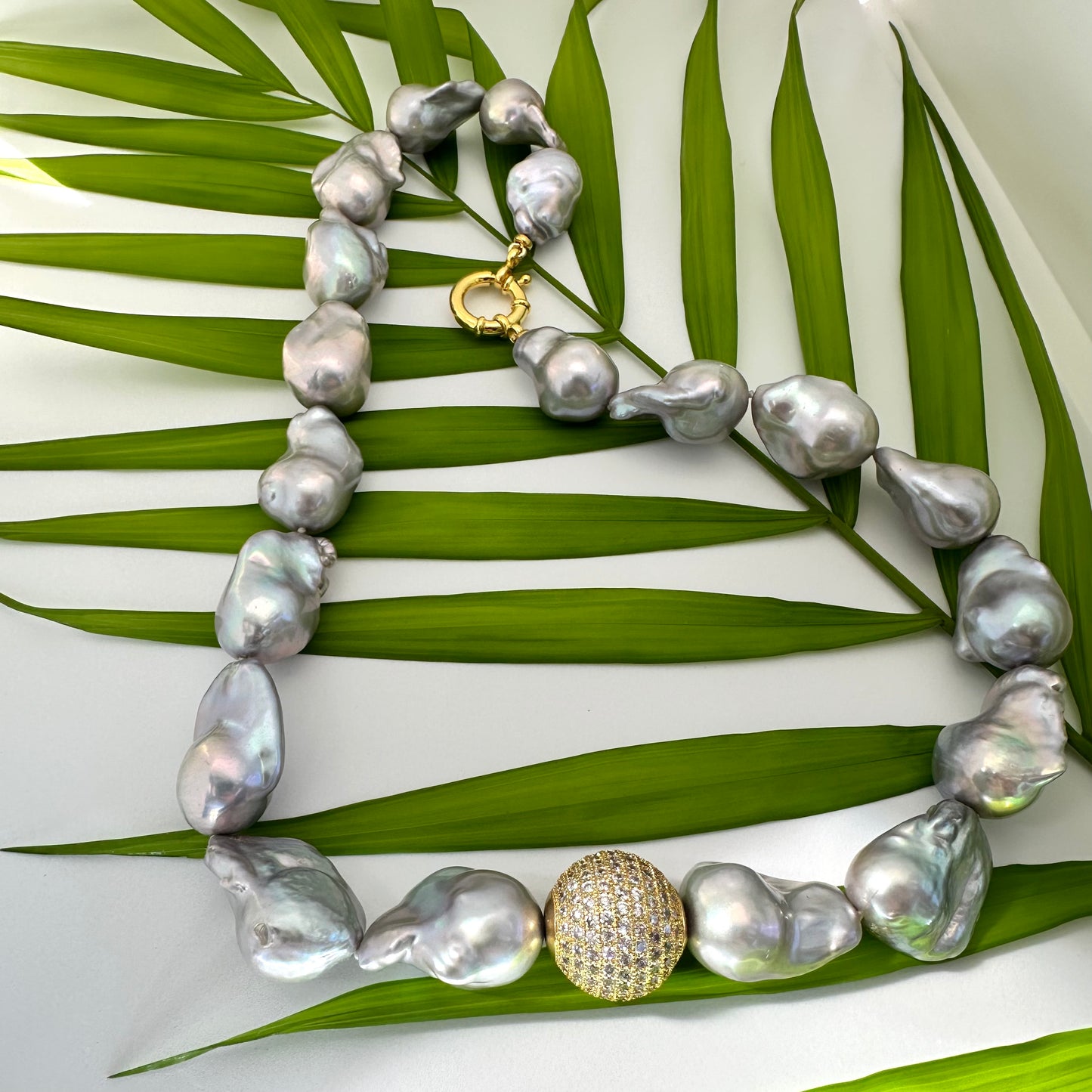 Handmade silver grey baroque pearl necklace detail on green leaf backdrop