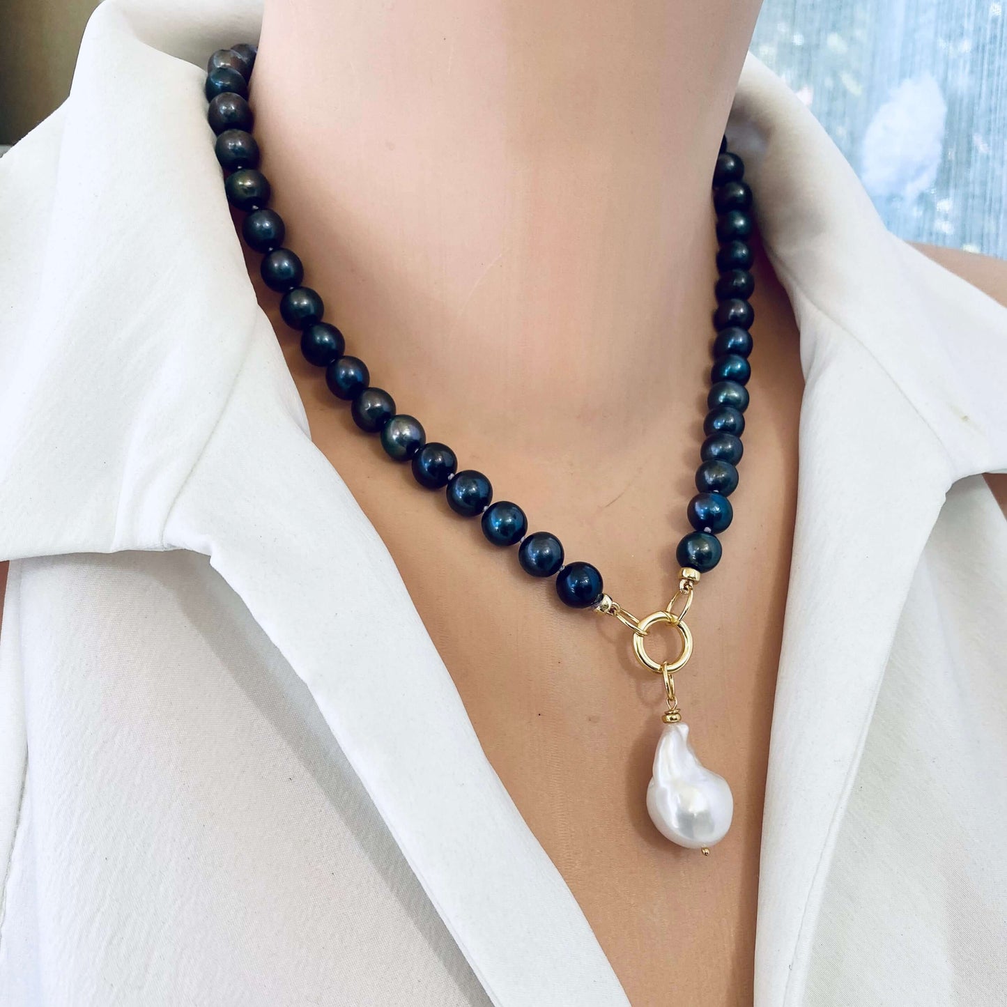 Side view of black pearl necklace with baroque pendant on mannequin featuring white pearl pendant