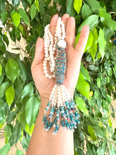 Carica l'immagine nel visualizzatore di Gallery, Bohemian Pearl Tassel Necklace held in hand, showcasing pearls, turquoise beads, and colorful tassels.