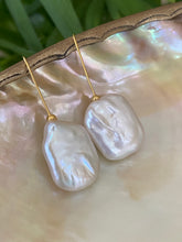 Load image into Gallery viewer, White freshwater pearl drop earrings in gold vermeil displayed on white pearl shell with green leaf background, designed and handmade in Canada.