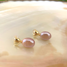 Cargar imagen en el visor de la galería, Heart Pearl Earrings – gold version close-up against white pearl shell