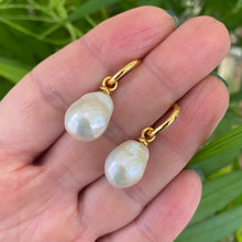 Cargar imagen en el visor de la galería, White Baroque Pearl Earrings – held by hand against natural green foliage