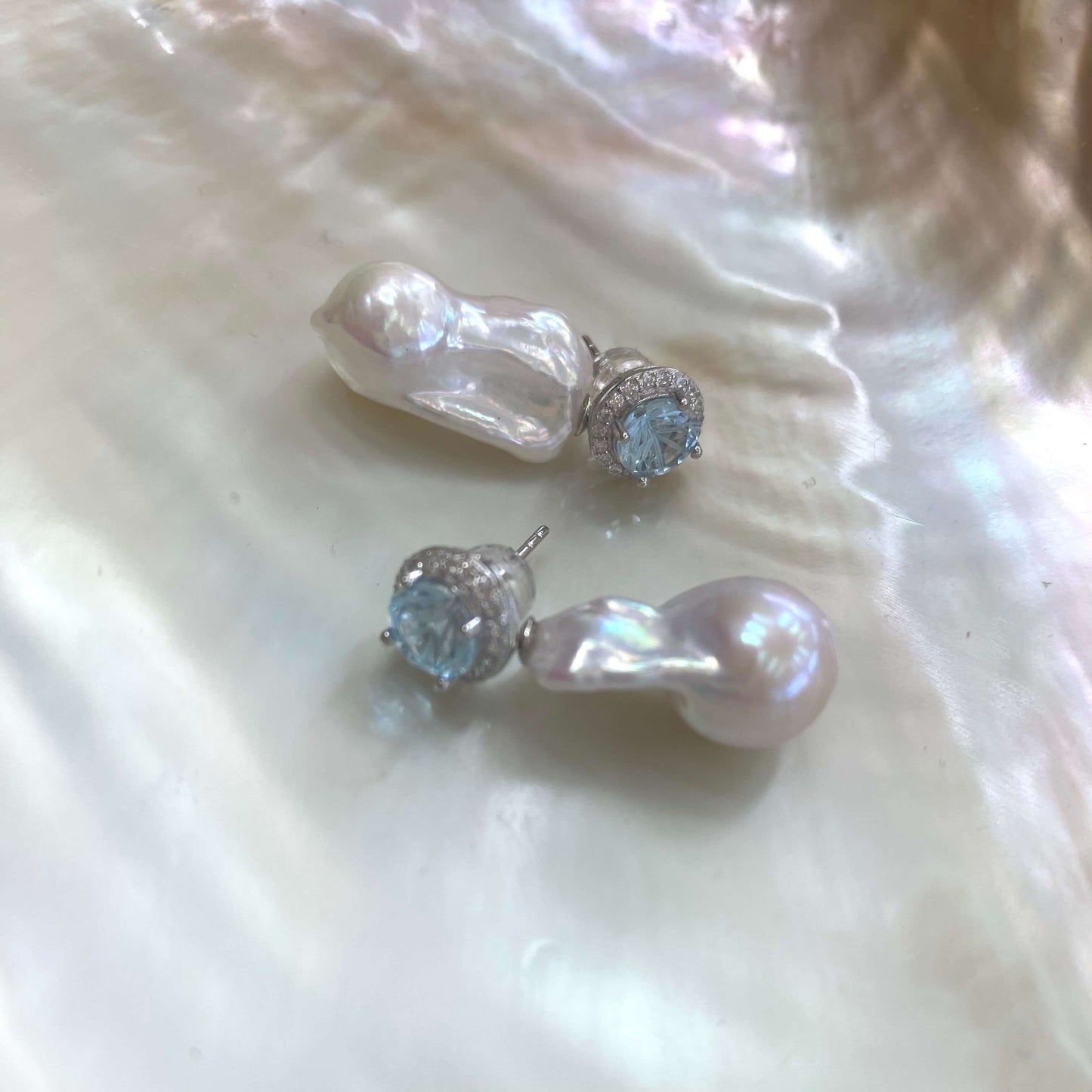 Handcrafted blue topaz pearl earrings with baroque pearls on shell background