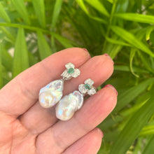 Carica l'immagine nel visualizzatore di Gallery, Emerald stud earrings with pearl drops held in hand against green leaf backdrop