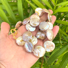 Cargar imagen en el visor de la galería, Large coin pearl necklace held in hand against green leaf background