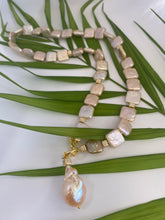 Carica l'immagine nel visualizzatore di Gallery, Golden baroque pearl toggle necklace displayed on green leaf branch — elegant handcrafted pearl jewelry photographed in natural light