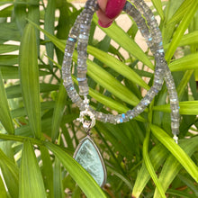 Load image into Gallery viewer, Labradorite aquamarine pendant necklace with aquamarine gemstone held in hand against leafy background — elegant artisan jewelry by Loulia Pearl Jewelry