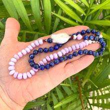 Lade das Bild in den Galerie-Viewer, Lapis lazuli and baroque pearl necklace held in hand against green leaves, natural gemstone jewelry.