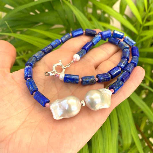 Lapis Lazuli Pink Rhodonite Baroque Pearl Necklace held in hand against green leaves — handcrafted gemstone and pearl jewelry by Loulia Pearl Jewelry