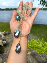 Lade das Bild in den Galerie-Viewer, Green Prehnite and Black Baroque Pearls Lariat Necklace held outdoors by a hand, showcasing its elegance and craftsmanship.