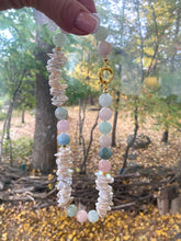 Cargar imagen en el visor de la galería, Aquamarine Morganite Necklace – held by hand against green foliage backdrop