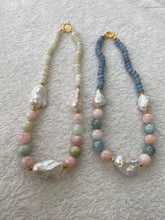 Cargar imagen en el visor de la galería, Morganite and jade necklace with baroque pearls beside blue gemstone necklace on white mat, showcasing color contrast and design variety.