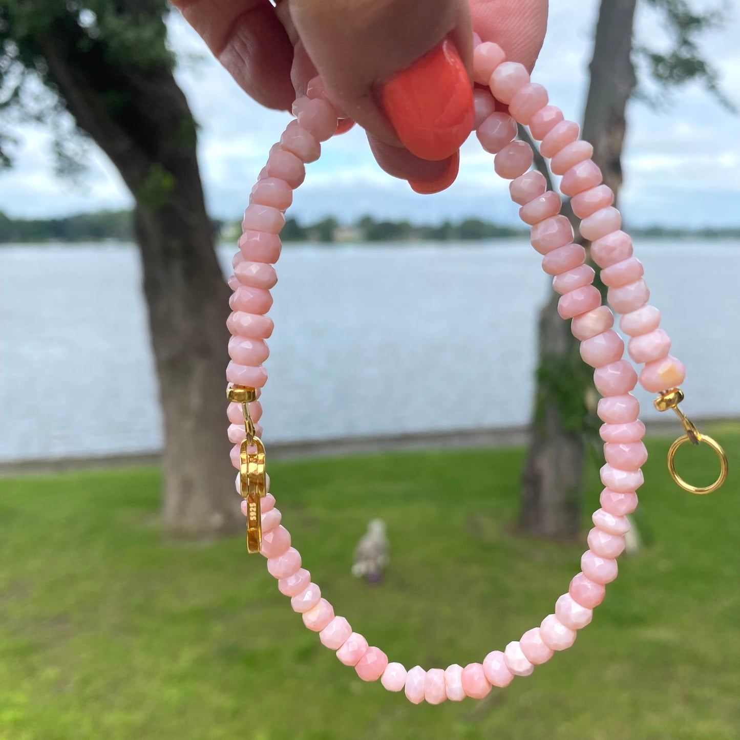 Pink opal short necklace held outdoors showing full length and soft pink gemstone color