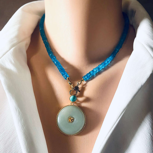 Hotan jade pendant with turquoise accent in gold vermeil, displayed on a mannequin wearing a blue beaded necklace.