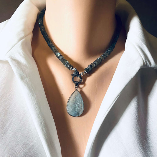 Aquamarine teardrop pendant in oxidized sterling silver worn on a necklace with beads, showcasing its organic beauty.