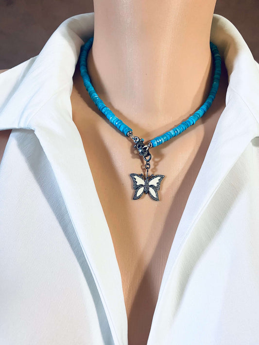 Enamel butterfly pendant with diamond pavé on a blue beaded necklace, showcased on a mannequin.