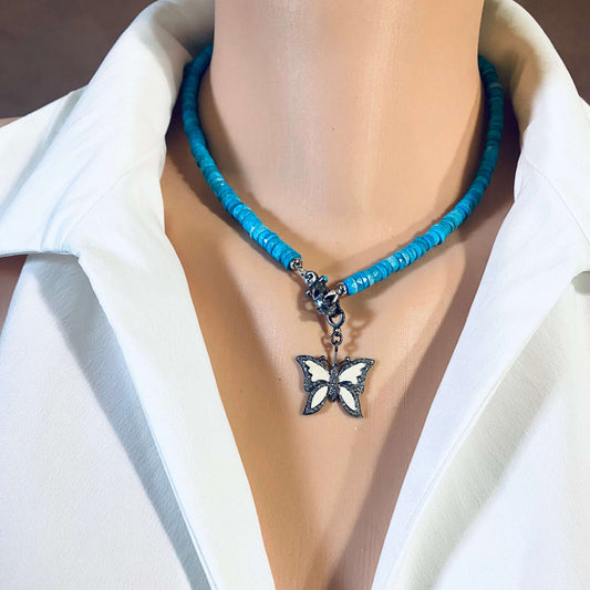 Enamel butterfly pendant with diamond pavé on a blue beaded necklace, showcased on a mannequin.