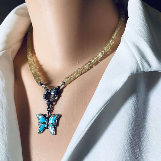 Blue enamel butterfly pendant with diamond pavé hanging from a necklace on a mannequin's neck.