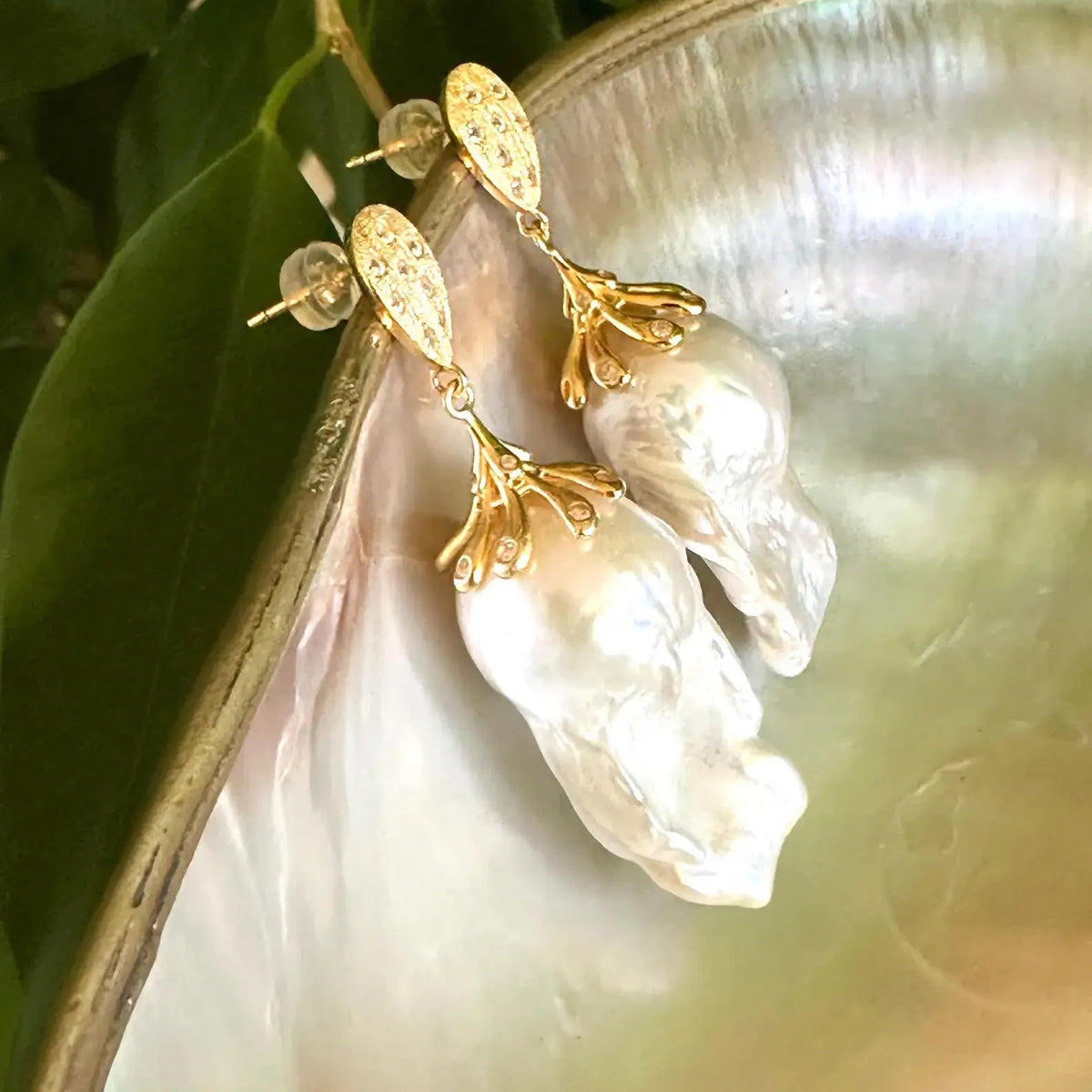 Detailed view of Baroque Pearl Gold Vermeil Earrings surrounded by pearls and green leaves — timeless handcrafted jewelry by Loulia Pearl Jewelry