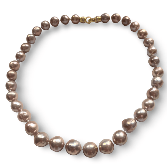 A strand of irregular baroque pearls in a dusty mauve-purple hue with a gold clasp, displayed on a clean white background.