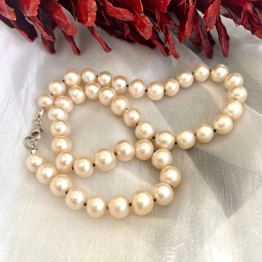 Off white pearl choker necklace displayed on white cloth