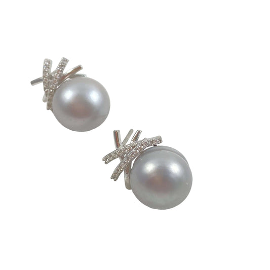 A pair of silver stud earrings featuring a large, round gray pearl set in a silver leaf-like halo with small clear stones, shown on a light gray background.